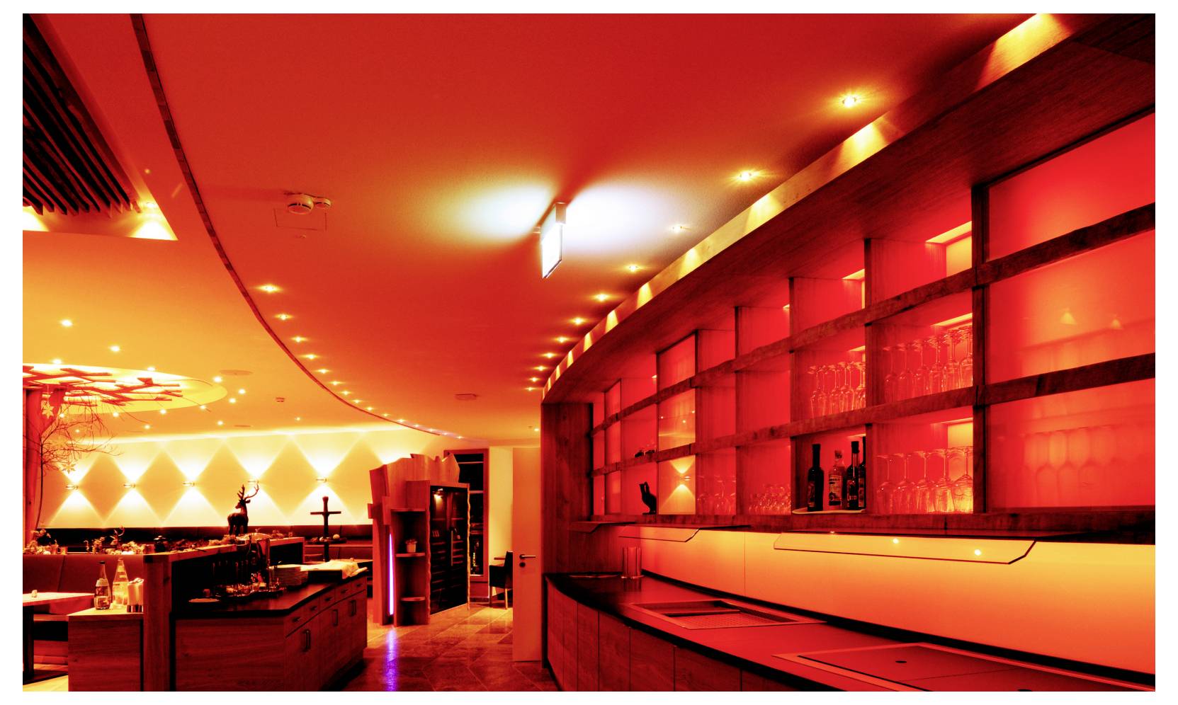 Intérieur moderne de restaurant ou de bar à l'éclairage chaud orange-rouge, avec un plafond incurvé et un long mur équipé d'étagères et de vitrines.