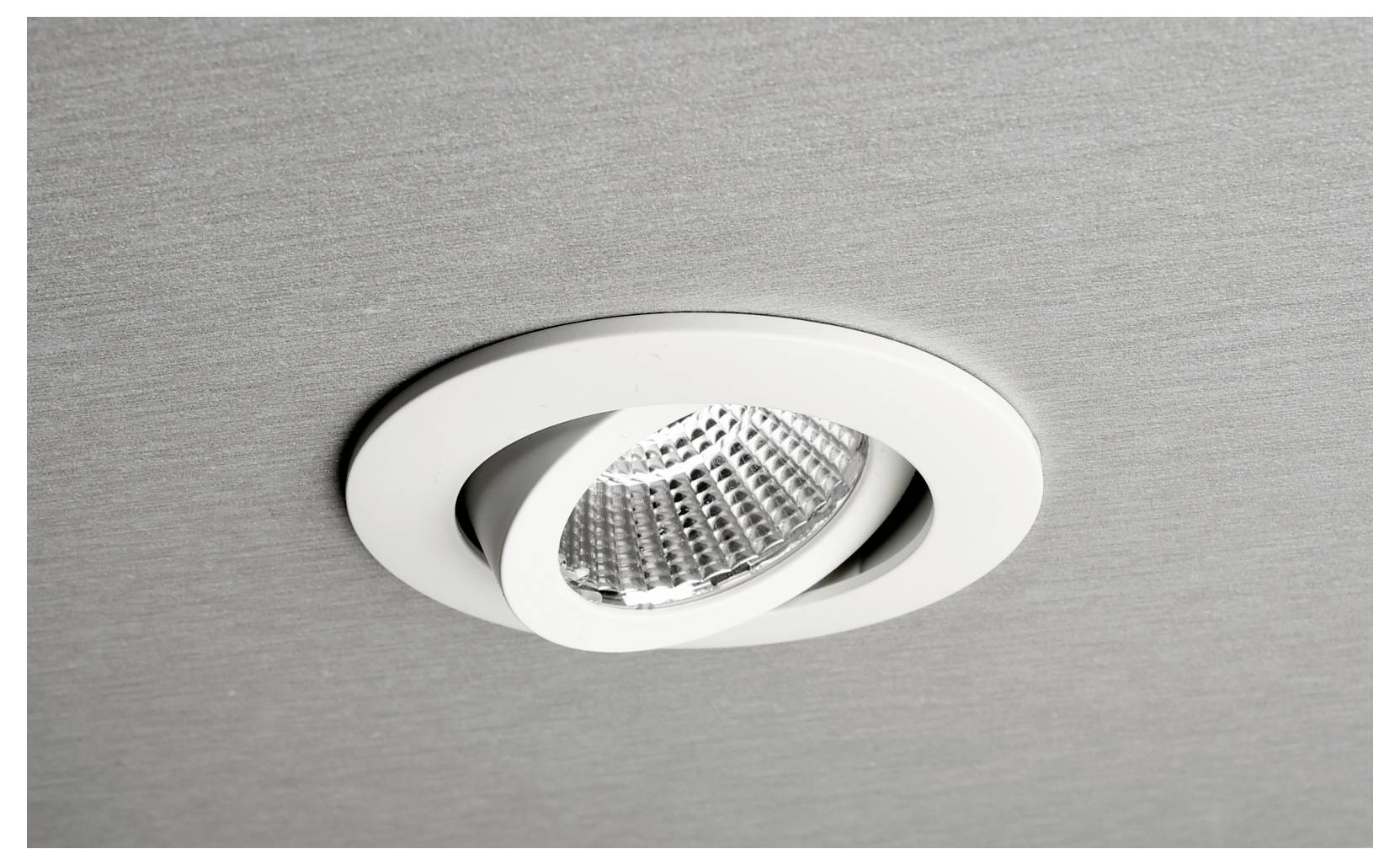 Spot orientable encastré blanc dans un plafond en métal brossé