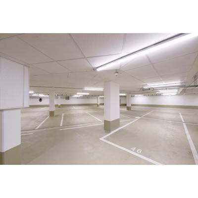 Parking de garage souterrain vide, bien éclairé, avec plusieurs places de stationnement marquées et des flèches au sol.