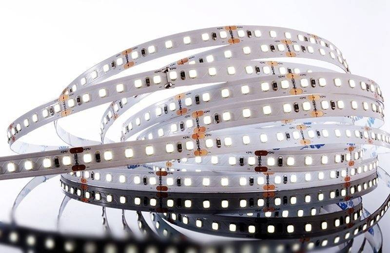 Une bande lumineuse LED enroulée sur une surface réfléchissante devant un fond clair.