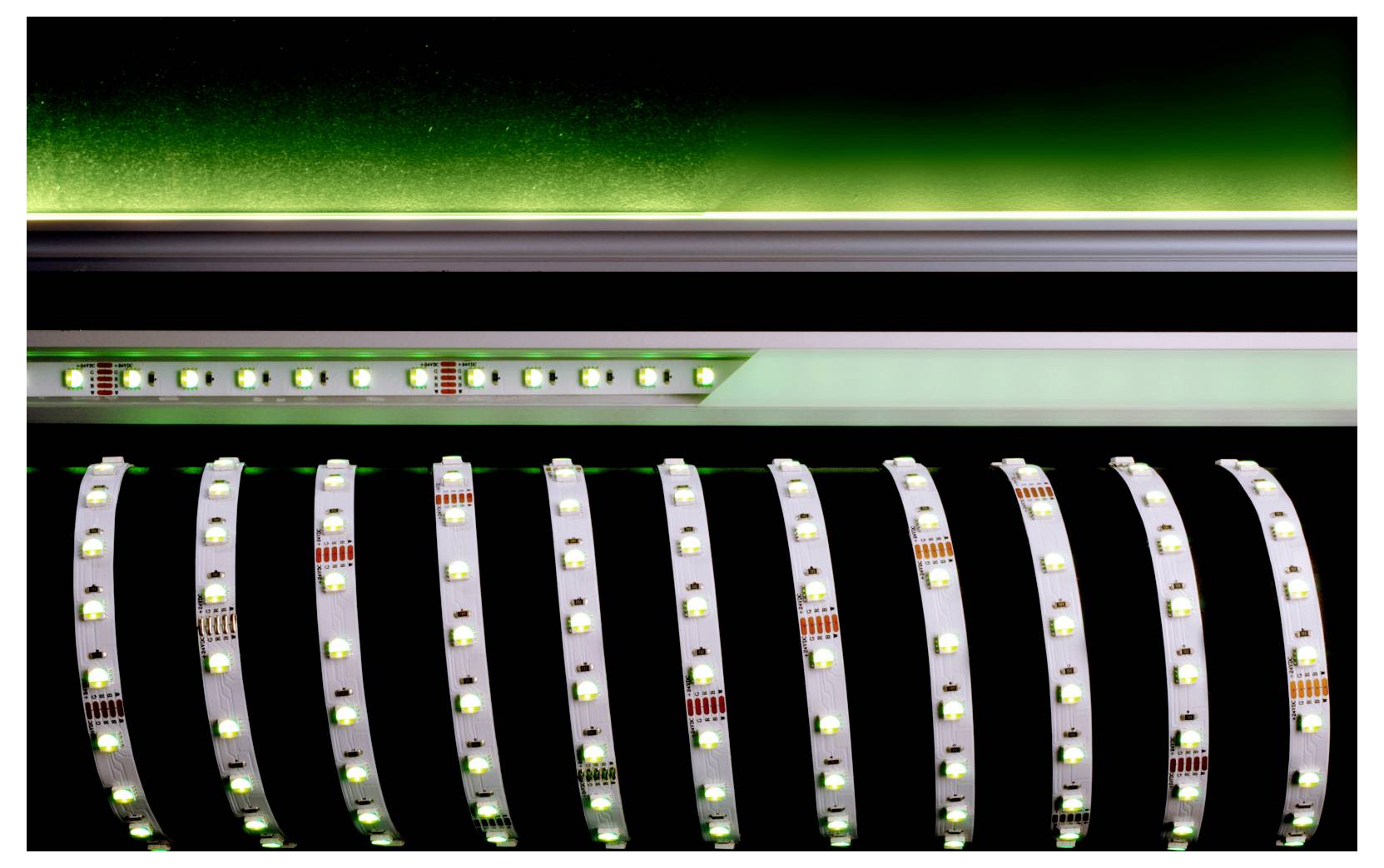 Gros plan de bandes LED ou de circuits imprimés flexibles qui brillent en vert sur un fond sombre.