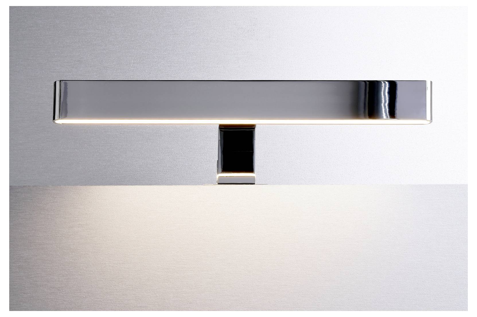 Applique murale moderne en chrome diffusant une lumière douce sur un mur gris clair et un panneau inférieur.