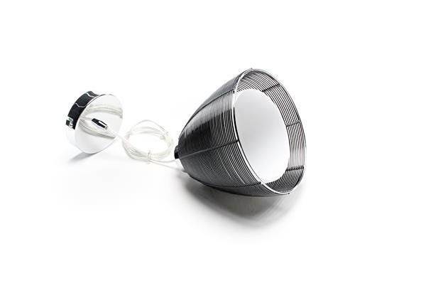 Abat-jour et douille en treillis métallique noir et blanc, reliés par un câble, posés sur un fond blanc.