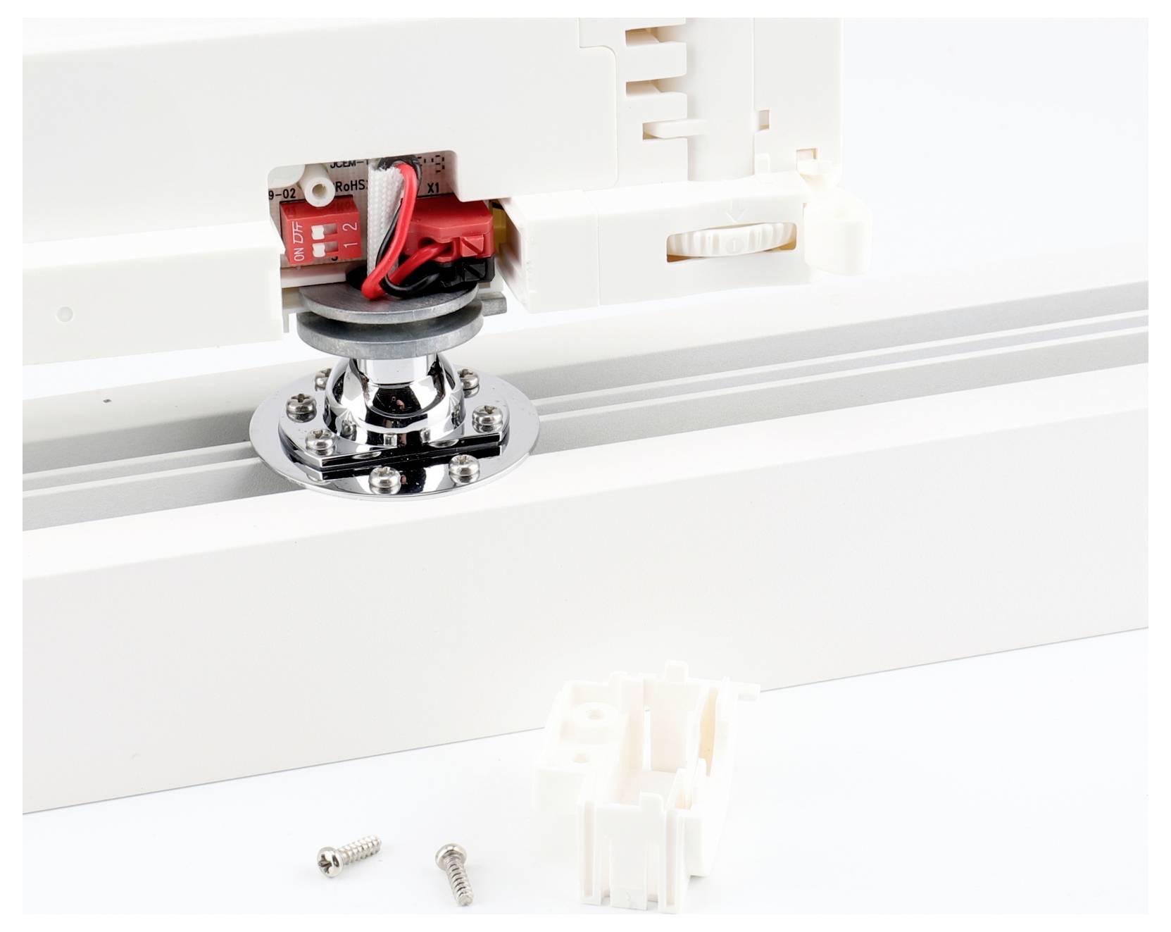 Gros plan d'un module de capteur électronique rouge monté sur un support en plastique blanc, avec deux vis desserrées et un petit connecteur blanc en dessous.