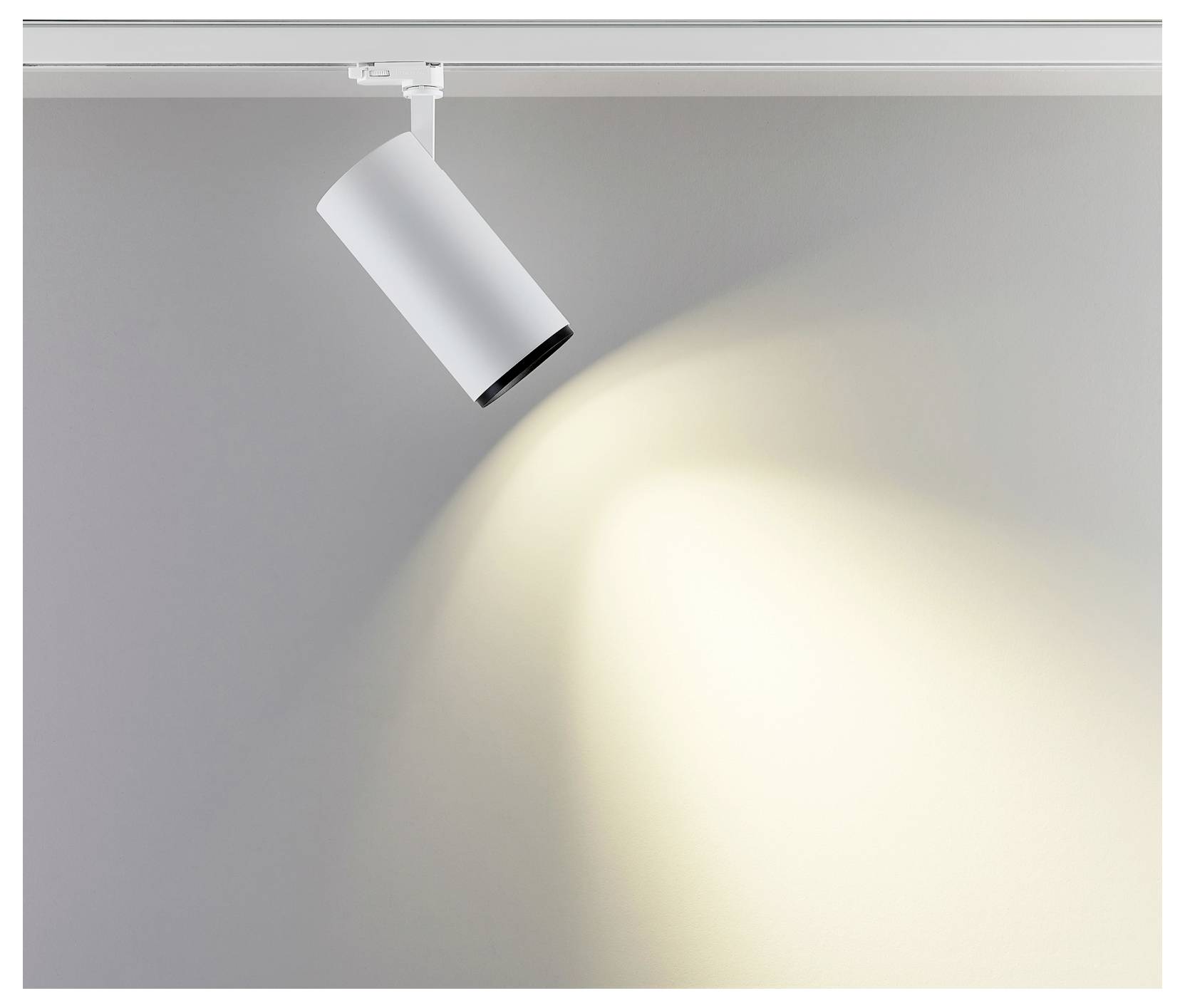 Spot sur rail blanc projetant un faisceau de lumière chaude sur un mur et un plafond gris