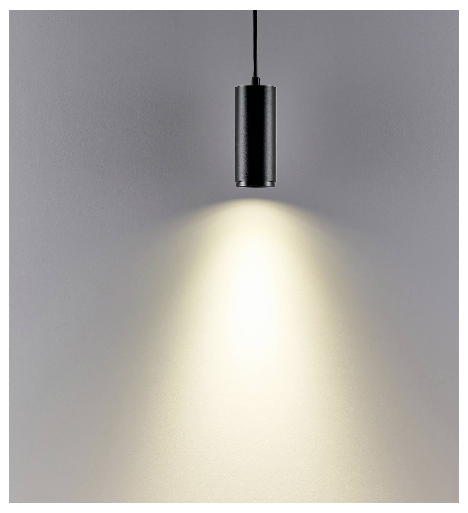 Suspension noire diffusant un faisceau chaleureux en forme de cône sur un mur gris.