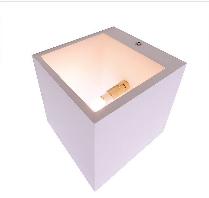 Une boîte blanche ouverte contenant une ampoule à l'intérieur, diffusant une lumière douce et chaleureuse, est posée sur une surface plane.