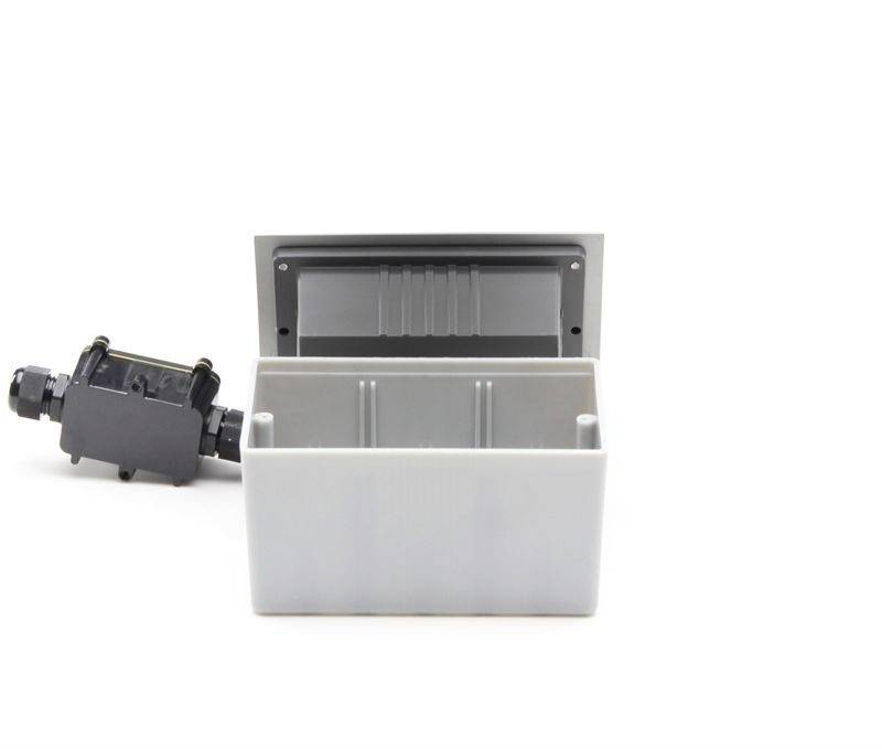 Boîtier gris ouvert avec connexion électrique noire, adapté aux connexions de câbles dans des applications industrielles.