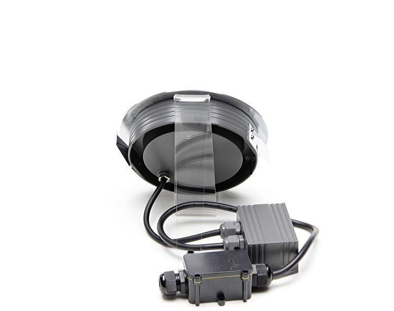 Connecteur électrique rond noir et argent avec écran transparent et boîtier de protection gris attaché, sur fond blanc.