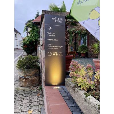Pierre indicatrice portant l'inscription 'Müller Kern', signalant un domaine viticole, une vinothèque et des appartements de vacances. L'environnement montre des plantes et des bâtiments.