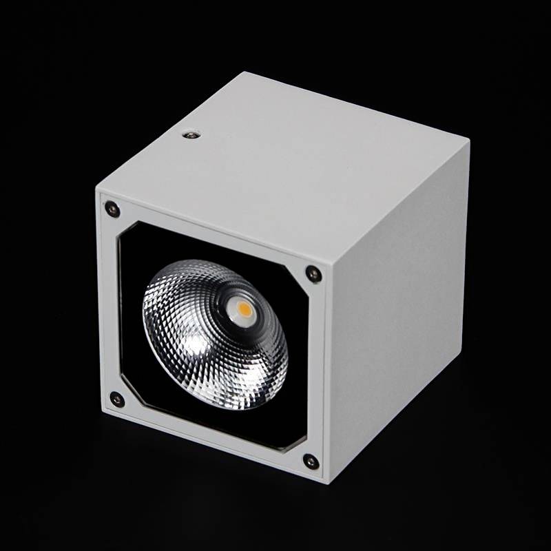 Lampe LED blanche cubique avec réflecteur intégré sur fond noir.