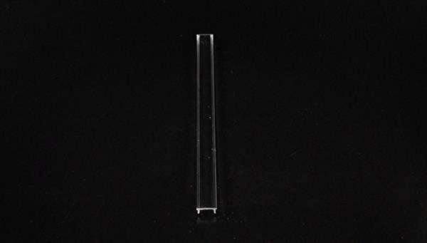 Un objet transparent, fin et allongé repose sur un fond sombre.