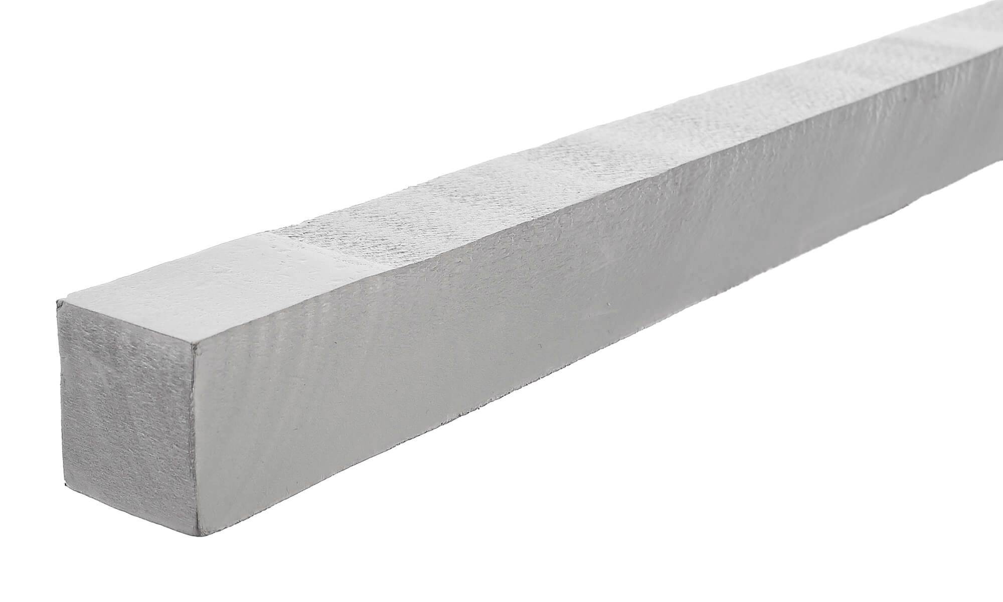 Une longue poutre rectangulaire en matériau clair, reposant sur un fond blanc.