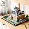Modèle Lego d'un château japonais avec des structures détaillées et un paysage de jardin environnant, exposé sur une étagère en bois.