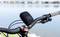 Sur l'image, on voit le guidon d'un vélo près d'un lac, avec un haut-parleur portable fixé dessus.