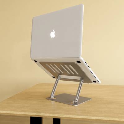 Un ordinateur portable est posé sur un support réglable en aluminium, qui se trouve sur une table en bois. L'écran est à moitié ouvert.