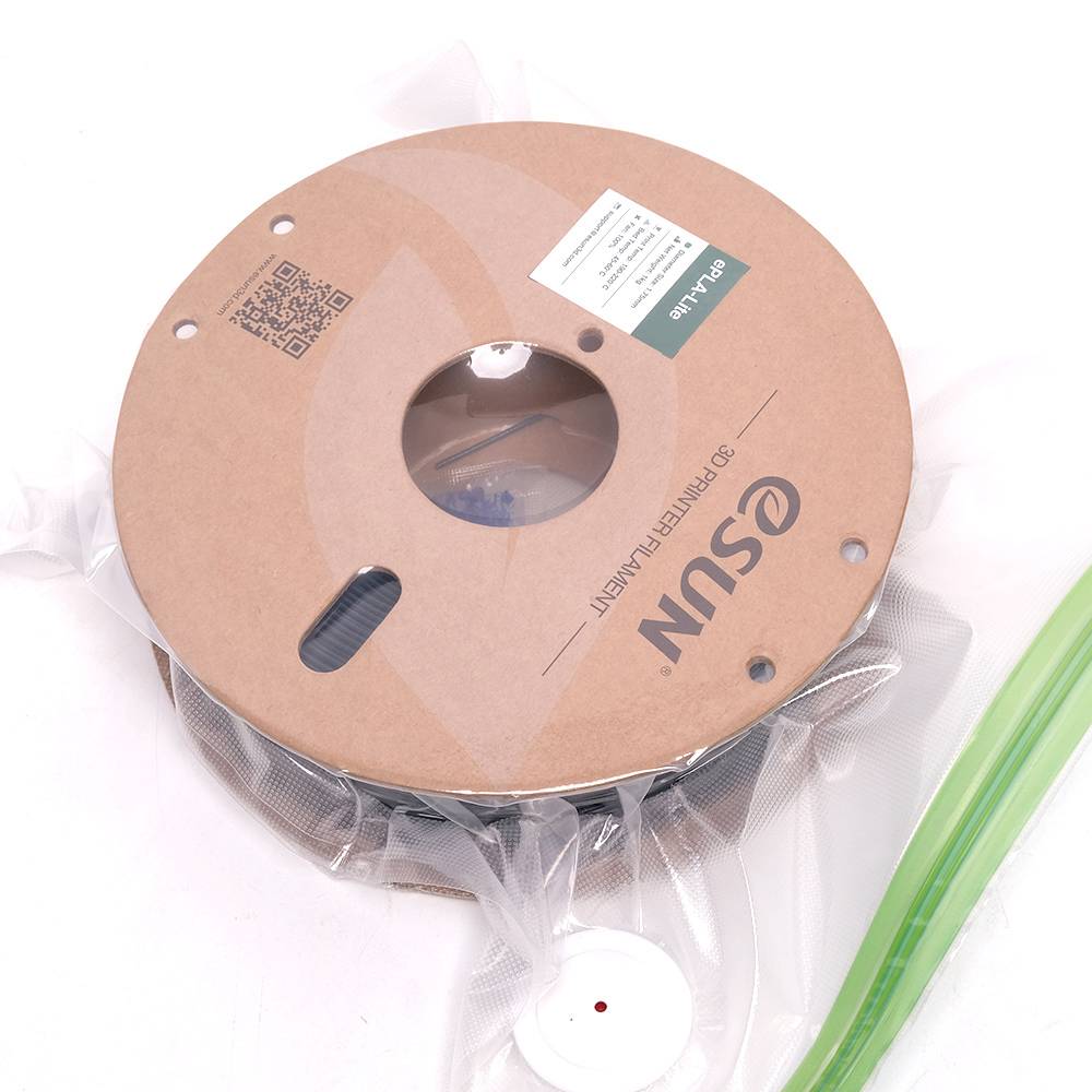 'Bobine de filament d'imprimante 3D dans un emballage marron, sécurisée avec un film plastique. Bobine de filament verte visible sur le côté.'