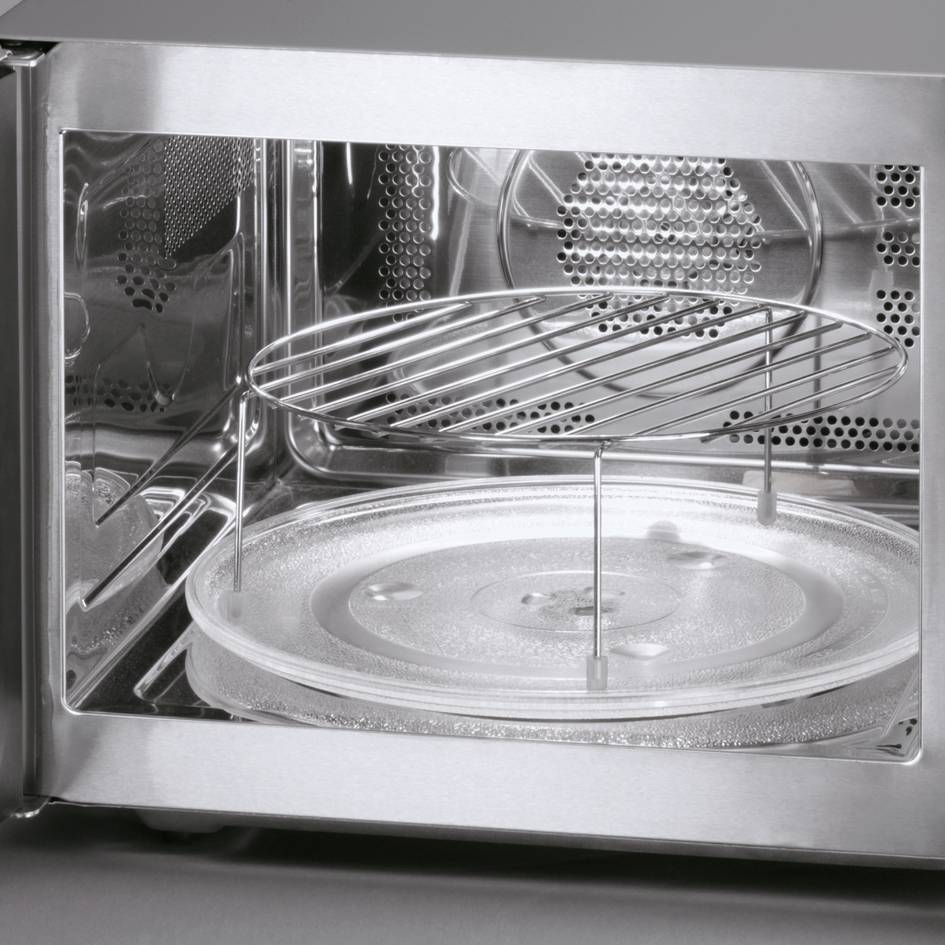 Four micro-ondes ouvert avec un plateau tournant transparent et une grille surélevée à l'intérieur.