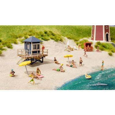 Petite plage miniature avec des baigneurs, des transats, des parasols, un poste de secours et un petit phare. Un requin miniature nage dans l'eau.