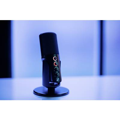 Un microphone noir monté sur un pied est posé sur une table devant un arrière-plan bleu flou.