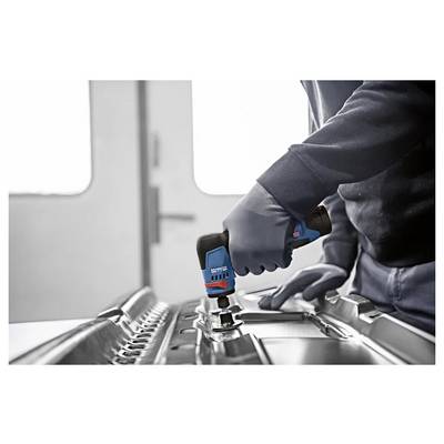 Ouvrier gantélé utilisant une perceuse électrique bleue pour fixer de la quincaillerie sur une surface métallique dans un atelier.