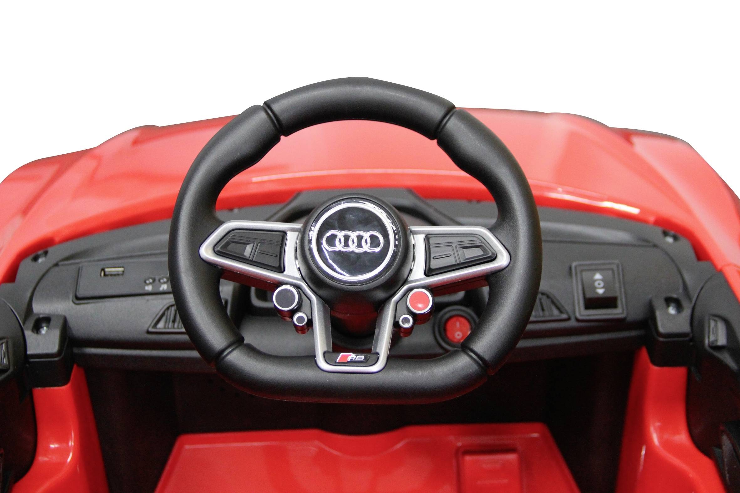 Une petite voiture jouet rouge avec un logo Audi sur le volant. L'intérieur révèle des détails finement conçus d'une vraie voiture.