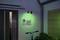 Mur d'une maison la nuit avec un éclairage vert, numéro de maison '27' à côté d'un interphone. Un vélo est placé au premier plan devant une fenêtre.