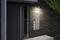 Une porte d'entrée moderne avec le numéro 27 et une plaque de sonnette. Un éclairage extérieur illumine le numéro de maison.