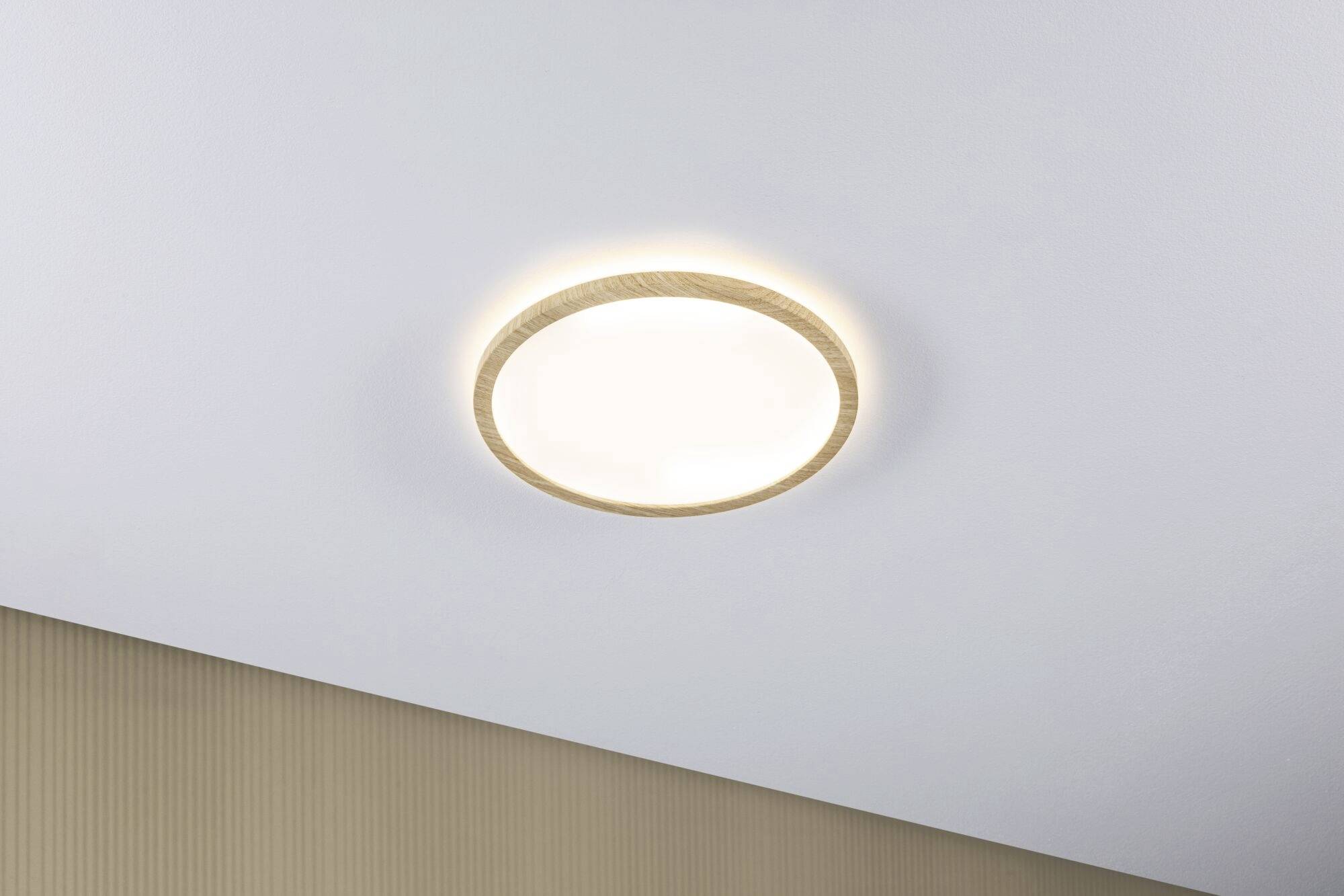Plafonnier rond en bois fixé au plafond. L'arrière-plan est un mur de couleur crème.