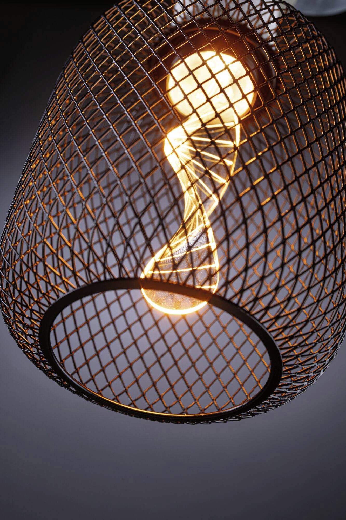 Lampe de plafond décorative avec grille métallique et ampoule incandescente qui diffuse une lumière chaleureuse dans la pièce.
