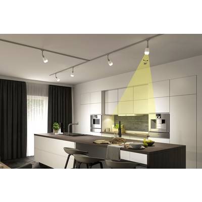 Cuisine moderne avec îlot, armoires blanches, four double et éclairage LED. Sur la table, il y a du pain, des citrons et de la décoration.
