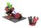 Robot composé de pièces Lego rouges et noires avec des éléments verts, monté sur une plaque noire. À côté, d'autres composants.