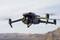 Un drone planant dans les airs au-dessus d'un paysage désertique. Des collines sablonneuses sont visibles en arrière-plan.