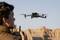 Une personne pilote un drone à l'aide d'une télécommande. Le drone survole un paysage désertique avec des formations rocheuses.