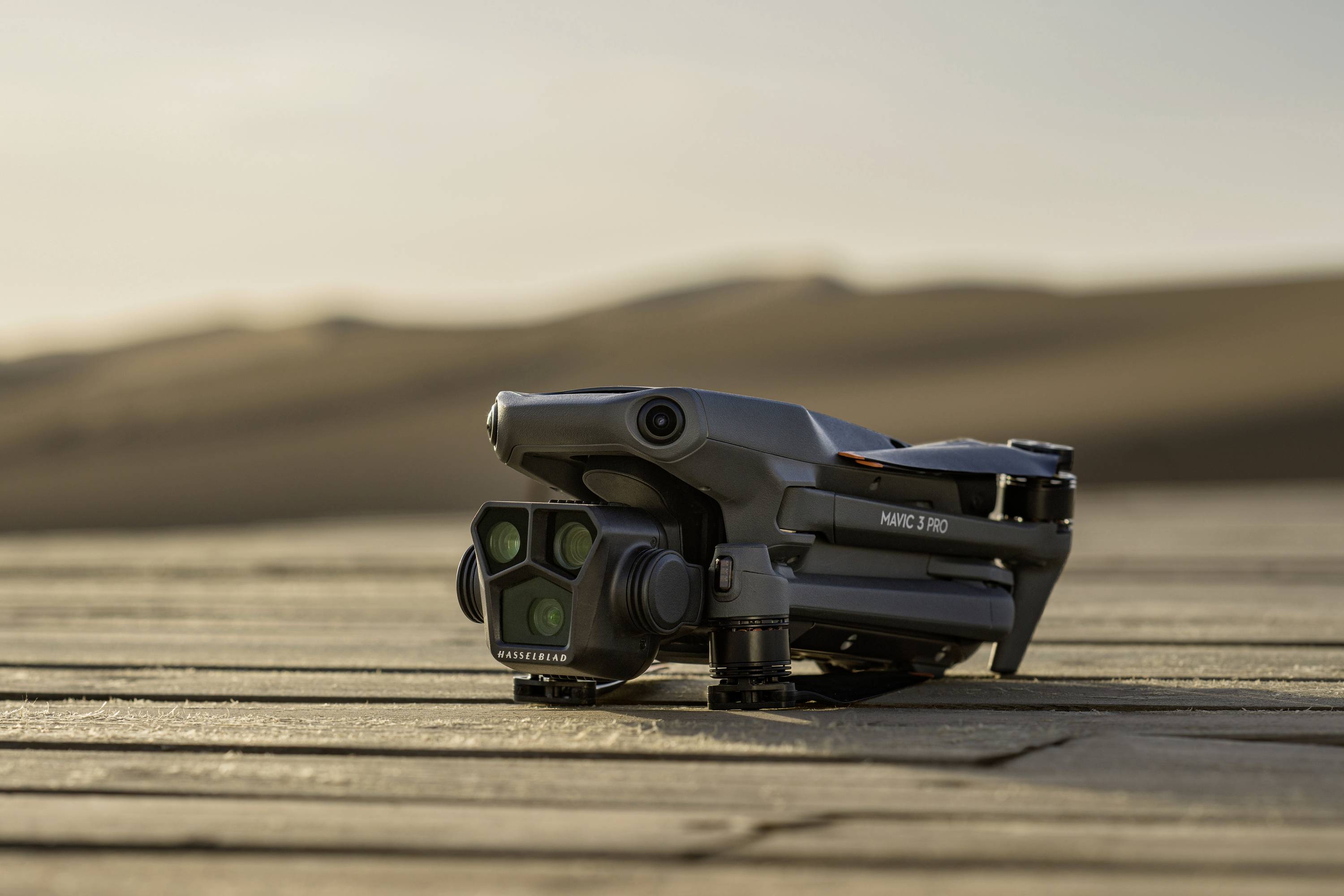 Un drone est plié et posé sur une surface en bois dans un environnement désertique, prêt à être déployé.