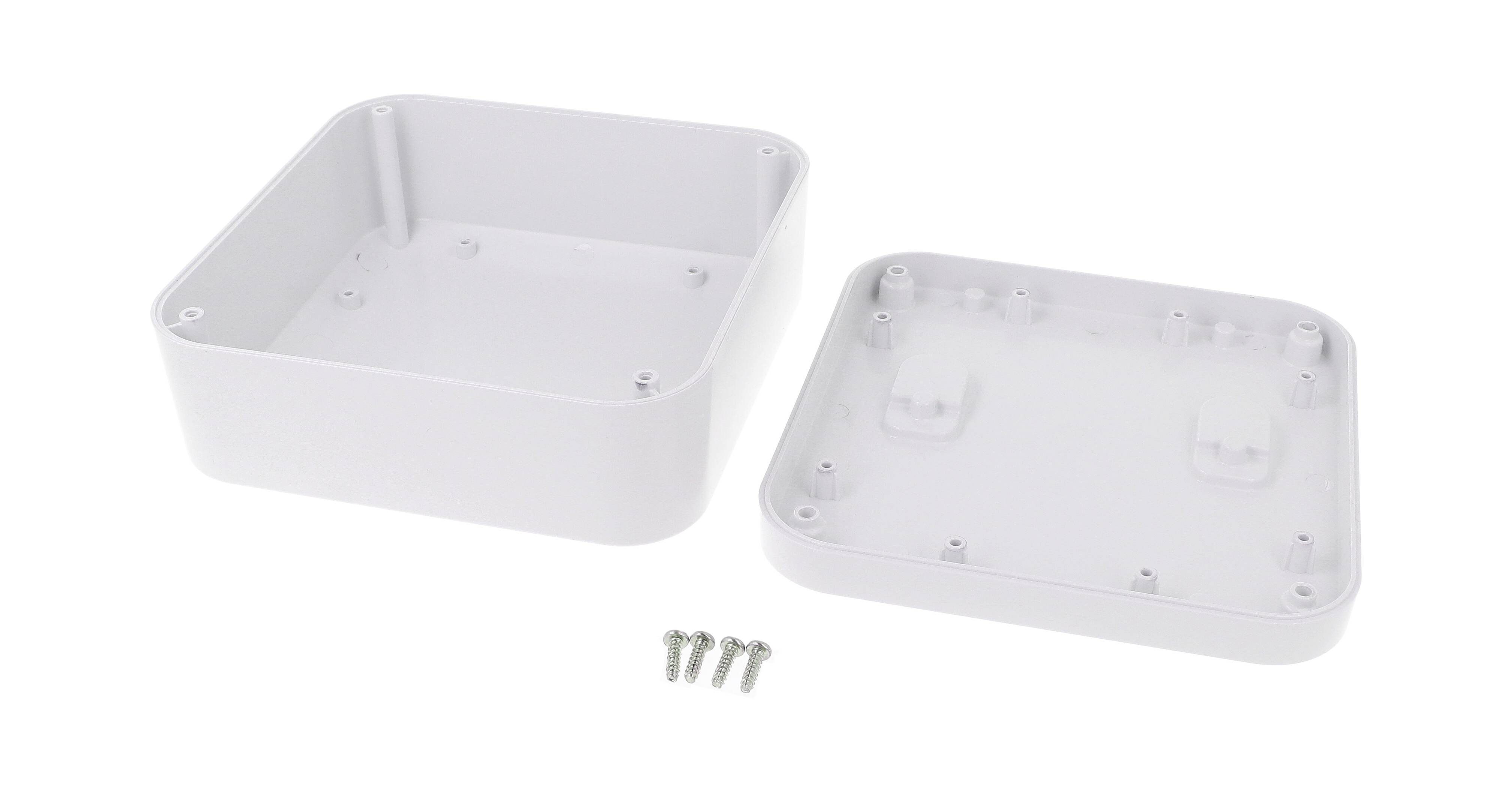 Un boîtier rectangulaire blanc en plastique, ouvert, montrant sa surface intérieure vide et quatre vis placées devant. Adapté pour les installations électroniques.