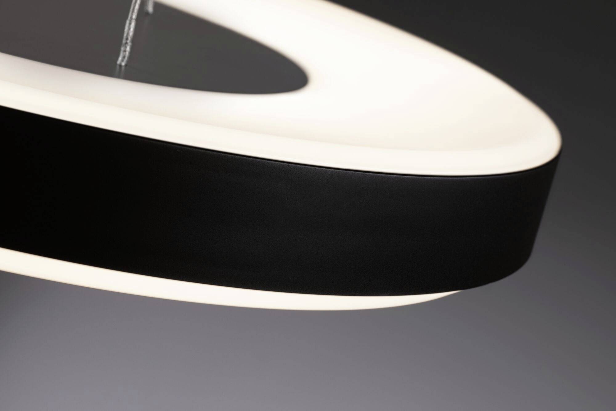 Luminaire suspendu rond et moderne avec cadre noir et intérieur lumineux, sur un fond gris.
