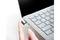 Une main pointe vers un périphérique USB connecté à un ordinateur portable. L'ordinateur portable est visible de côté, montrant son clavier.