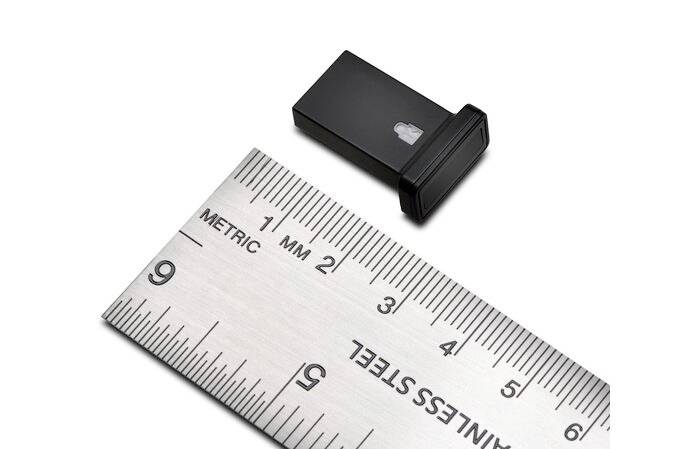 Une petite clé USB noire est posée à côté d'une règle en acier. Selon l'échelle de la règle, la clé USB mesure environ 2,5 cm de long.