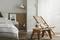 Une chambre lumineuse avec un lit à gauche et une chaise en bois à côté d'une petite table sur un tapis rond. La lumière du soleil pénètre par la fenêtre.
