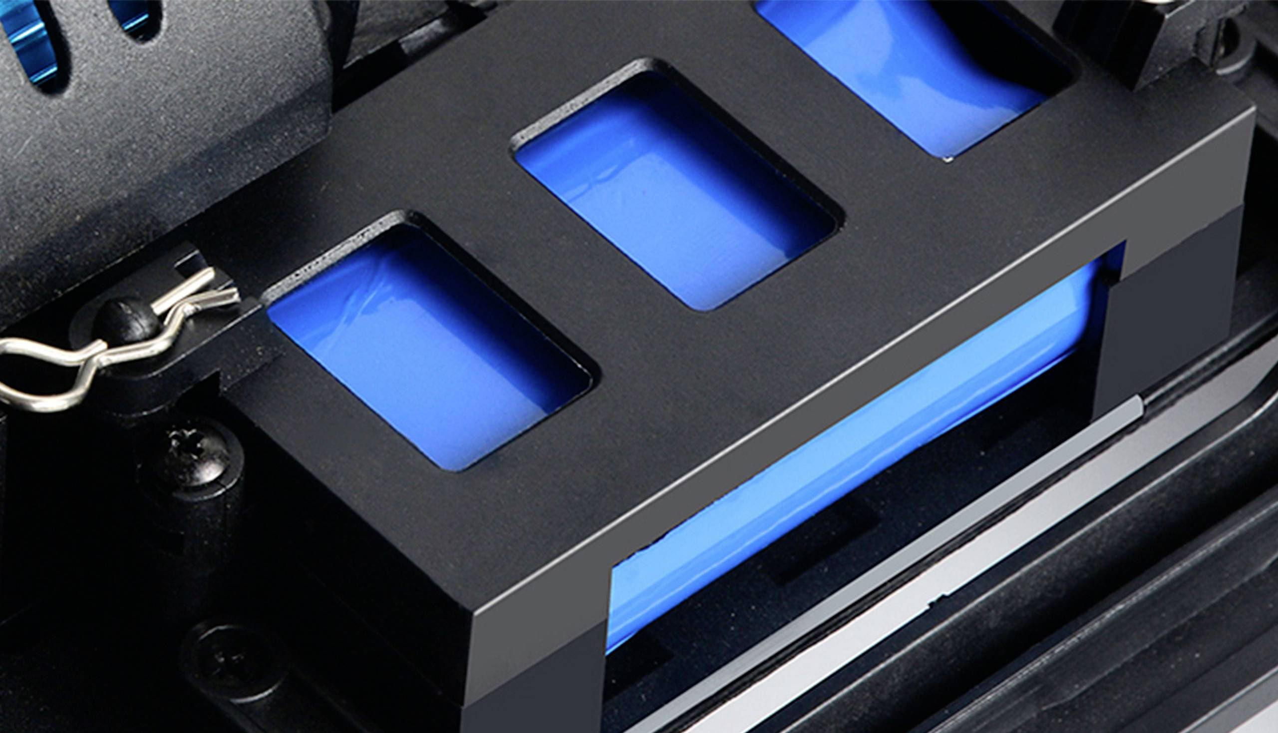 Gros plan d'une batterie dans un appareil, entourée d'un boîtier en plastique noir. Les cellules bleues sont partiellement visibles.