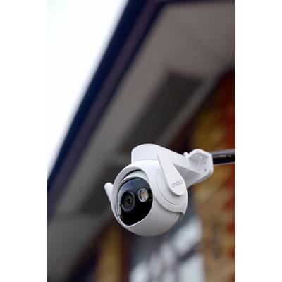 Caméra de surveillance en gros plan sur un mur de bâtiment, regardant vers le bas. Entourée d'un arrière-plan flou.