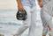 Un homme et une femme se promènent le long de la plage. L'homme tient un appareil portable de la marque 'Voltcraft' à la main.