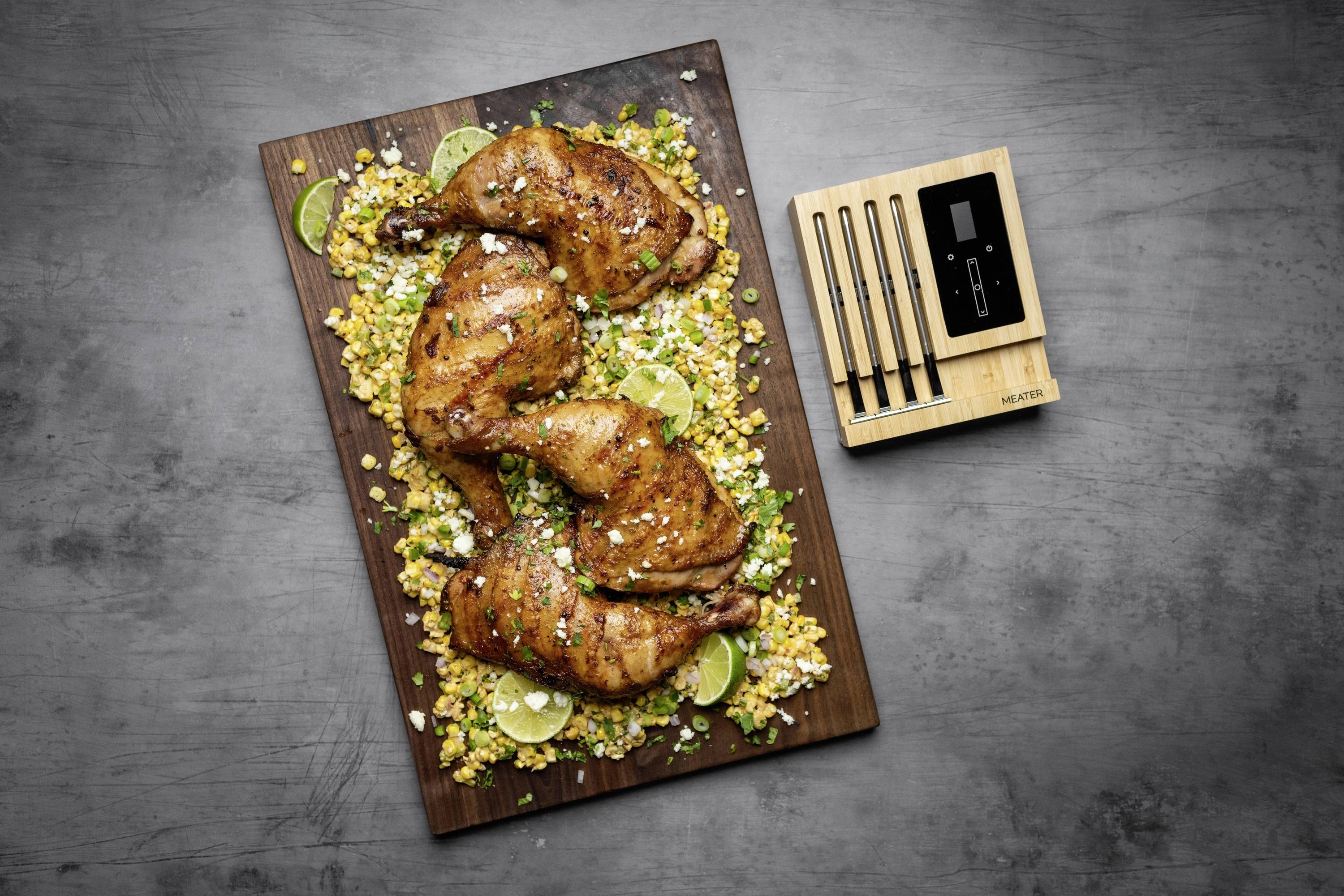 Cuisses de poulet grillées sur un lit de riz jaune aux herbes et tranches de citron vert, accompagnées d'un thermomètre de grill.