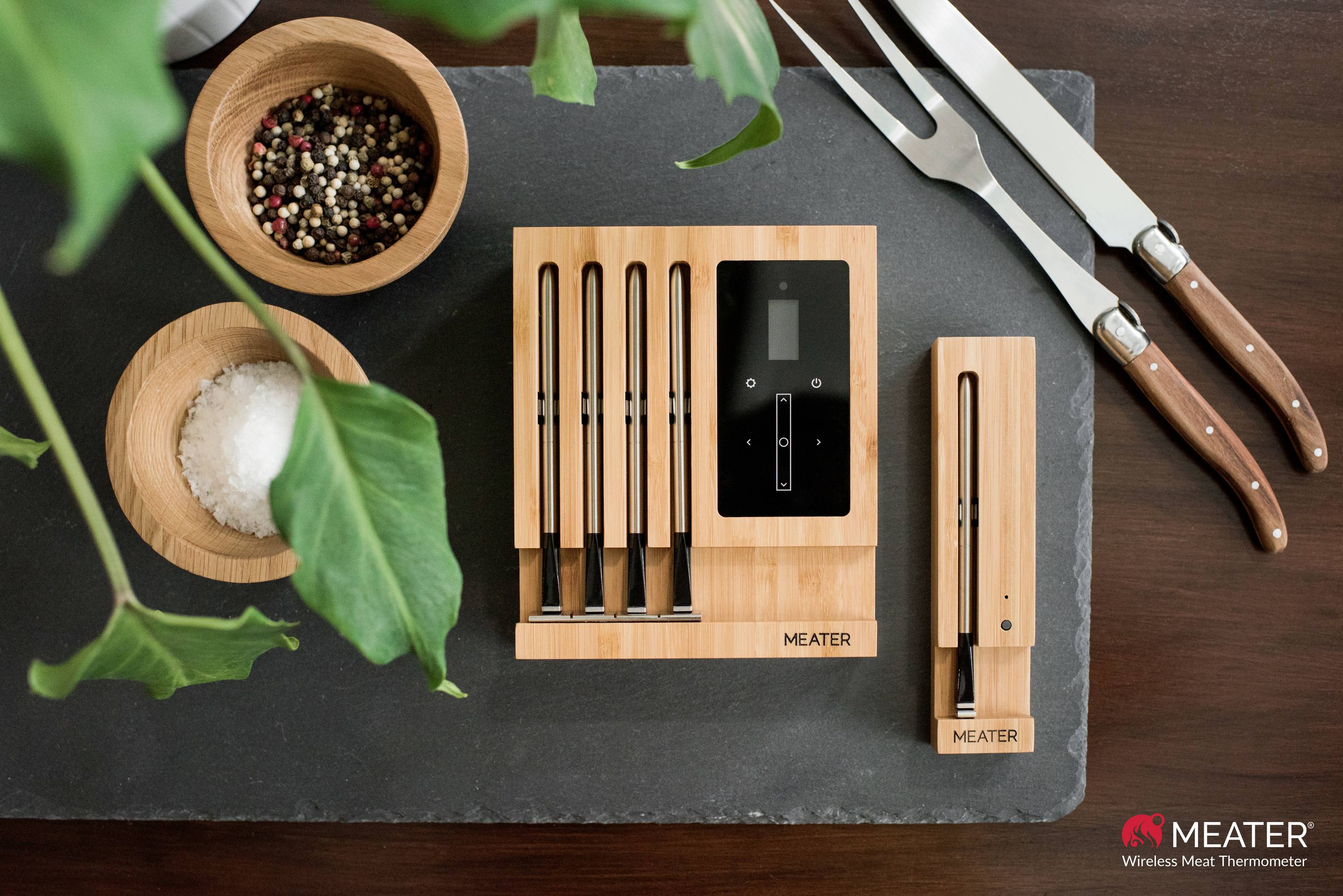 Un ensemble de thermomètres de barbecue sans fil sur des supports en bois, accompagné de coupelles d'épices. Ils sont posés sur un support sombre.