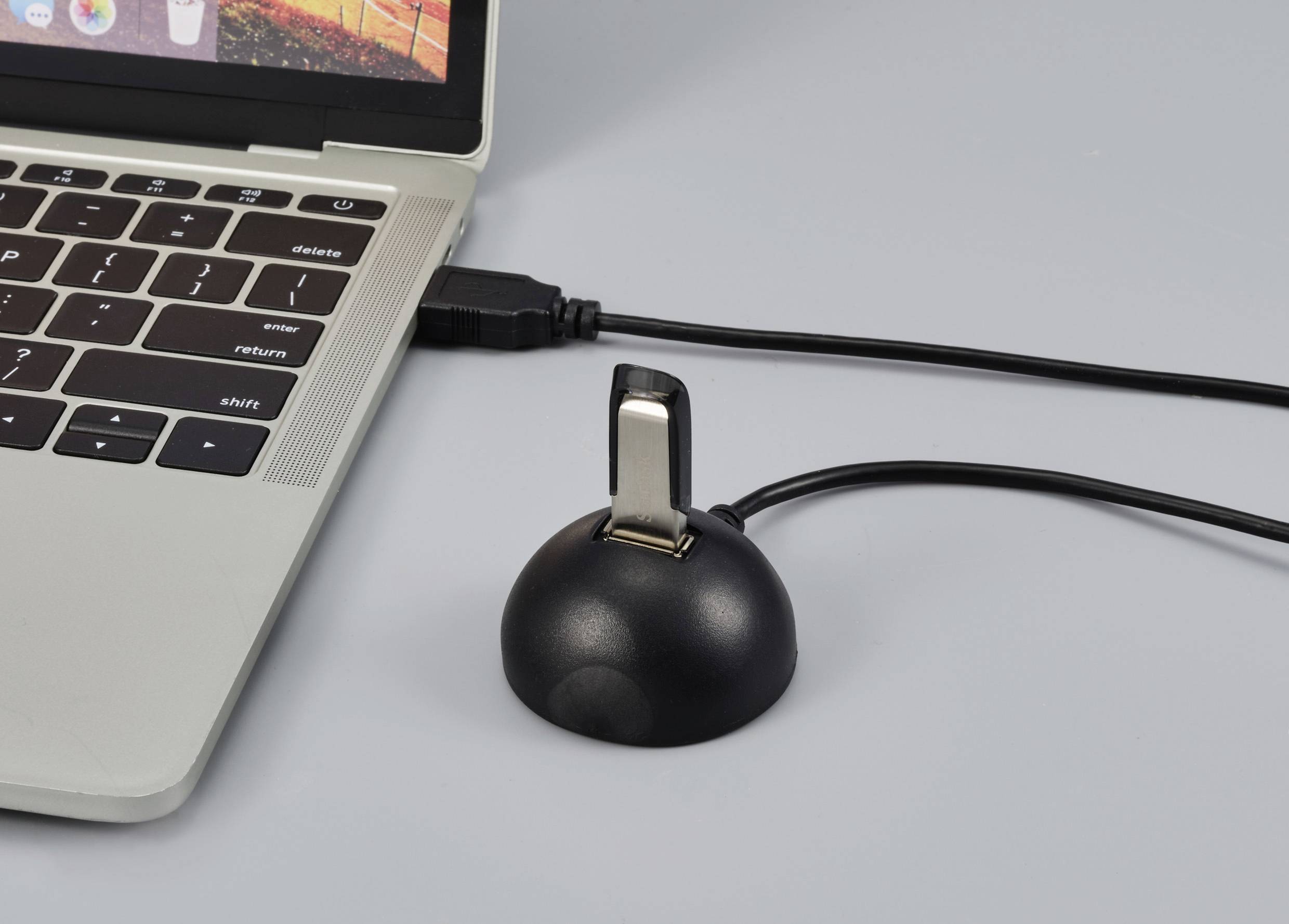 Une clé USB est branchée dans un adaptateur noir qui est relié à un ordinateur portable par un câble.