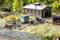 Un modèle de paysage miniature montre un dépôt ferroviaire avec une caravane de chantier bleue, des rails et des personnes travaillant à proximité, avec des arbres en arrière-plan.