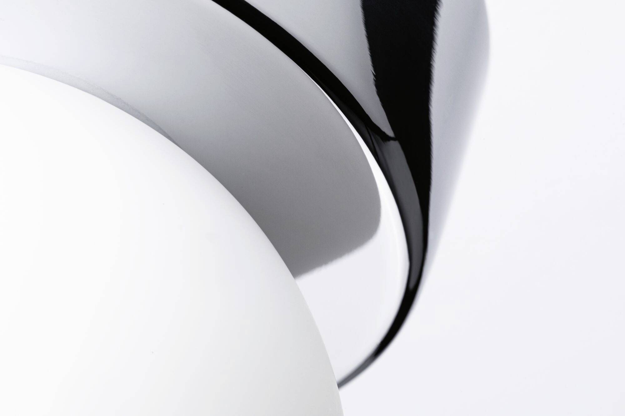 Gros plan d'une sculpture moderne aux formes courbes et lisses, en contraste noir et blanc sur un fond blanc.