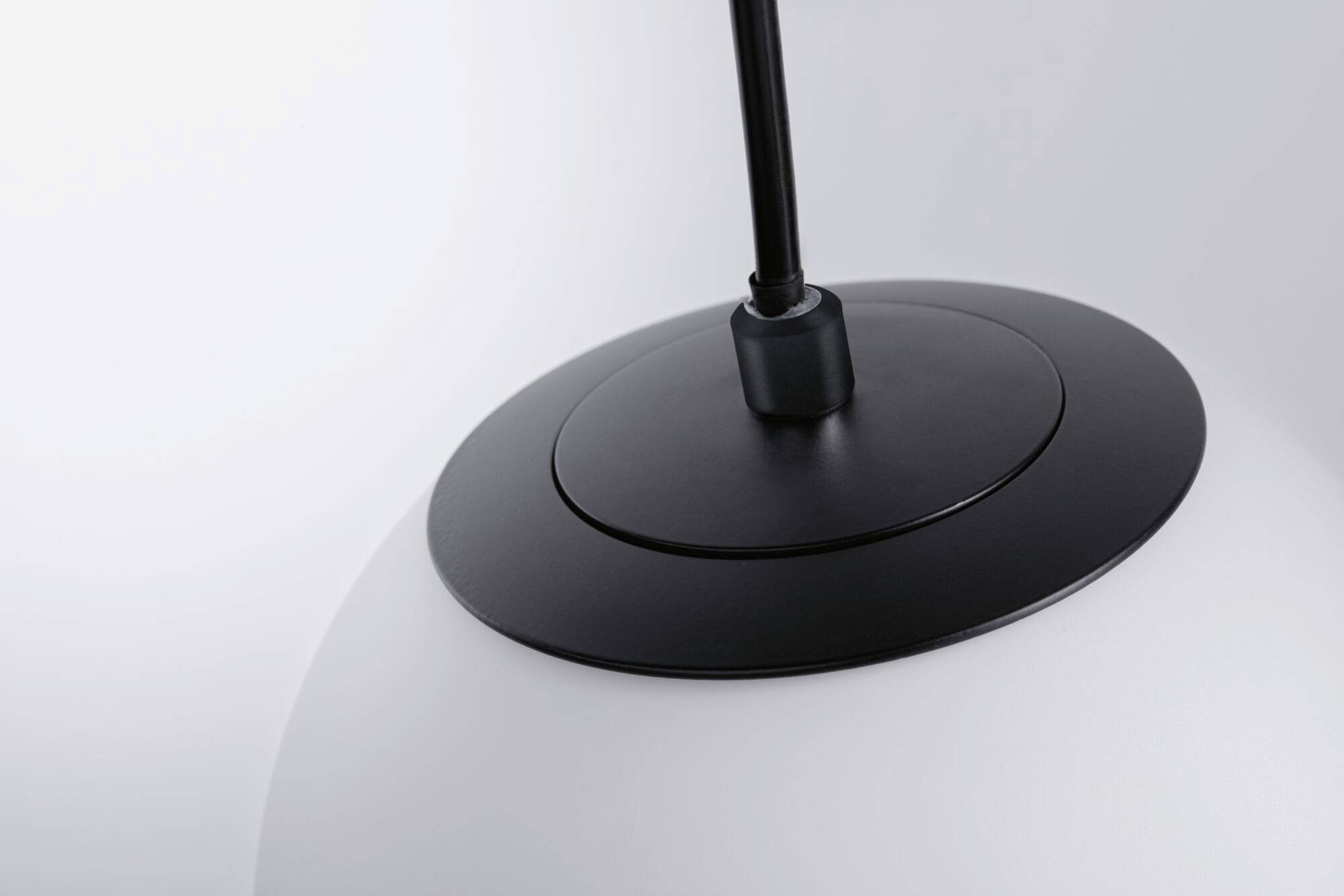 Un luminaire suspendu moderne avec un détail de fixation noir et un abat-jour blanc. Un design élégant et intemporel.