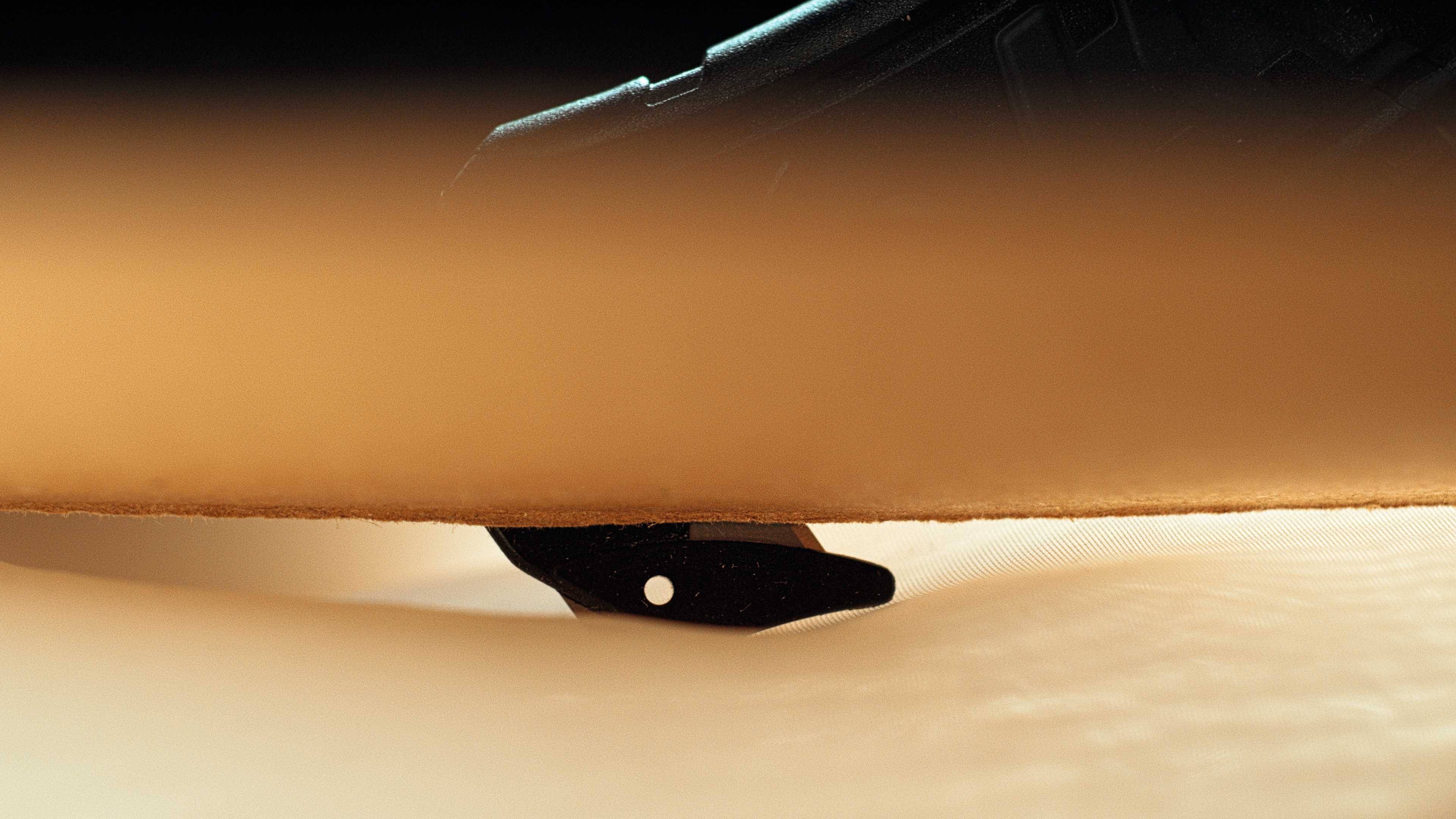 Une planche de skateboard avec un kicktail noir et un plateau en bois sur un revêtement de sol clair, avec un premier plan flou dans l'image.